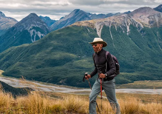 Man with hiking poles, walking on a trail with a lake in a distance