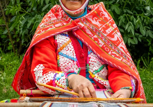 Woman weaving yarn, wearing traditional attire