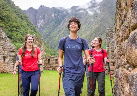 Group of men and women with walking poles, walking through stone ruins