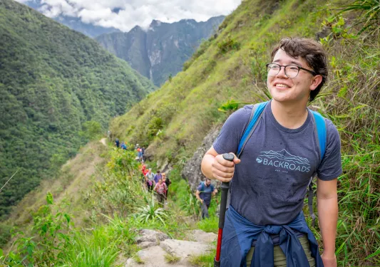 Man with a walking pole, ascending a narrow hilli