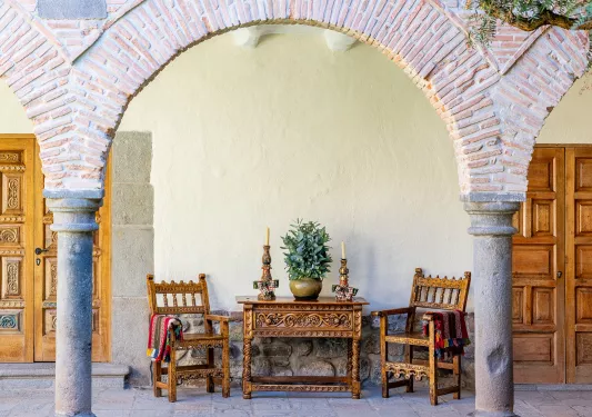 Stone arches on a patio, with wooden chairs and tables underneath