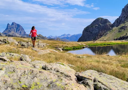 A hiker walks around a lake next to a mountain