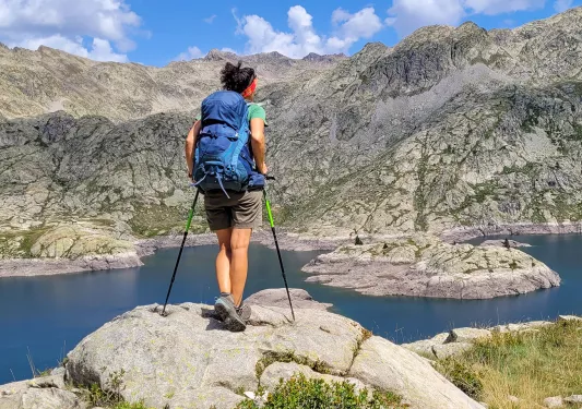 A hiker stops at a lake to look at the view