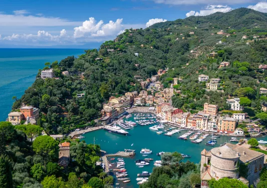 Sky view of the ocean with boats floating and a small town on a hill