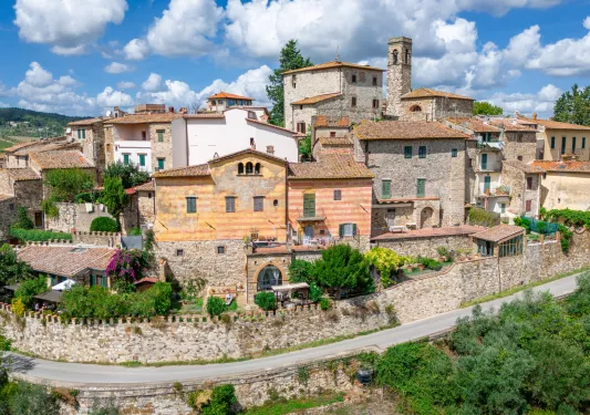 Exterior view of stone buildings along a road, with trees in front