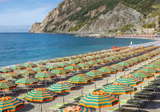 Rows of striped umbrellas and green chairs on the beach