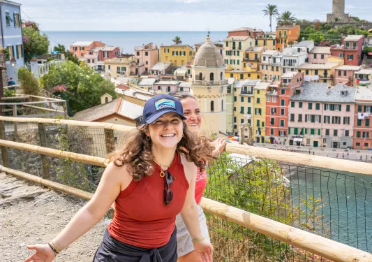Two women walking on a dirt trail with a town in the background