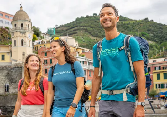 Two women and one man smiling while walking on a boat dock by the water