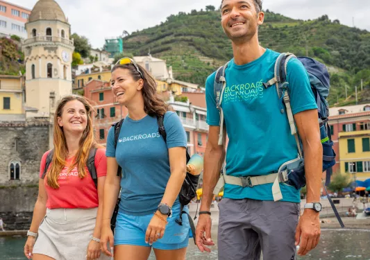 Two women and one man smiling while walking on a boat dock by the water