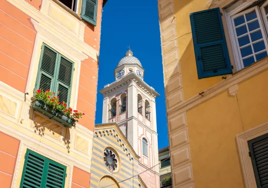 Orange buildings in the middle of a town, with a tall church bell tower in the center