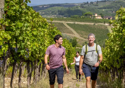 Two men smiling while walking through a crop field in the middle of a valley