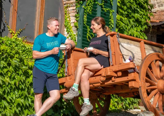 Man standing and smiling, while a woman is seated on the back of a wagon