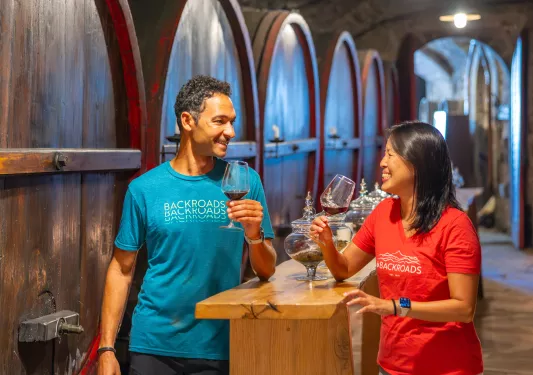 Man and women in a wine cellar, holding glasses of wine and smiling