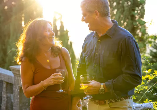 Man and woman smiling at each other, while holding glasses of wine