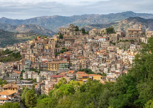 Large homes and apartment buildings along a hill, with mountains in the distance
