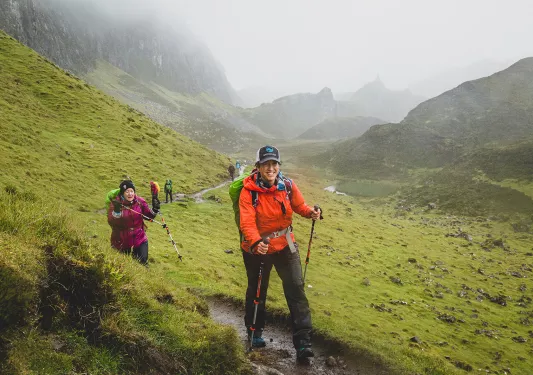 Group of people with walking poles, hiking along a mud and dirt trial