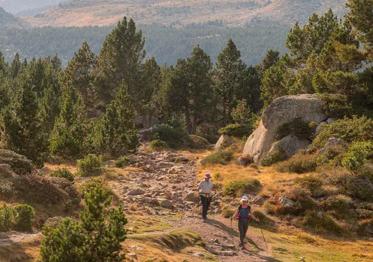 Two people descending a small hill towards a grassy valley