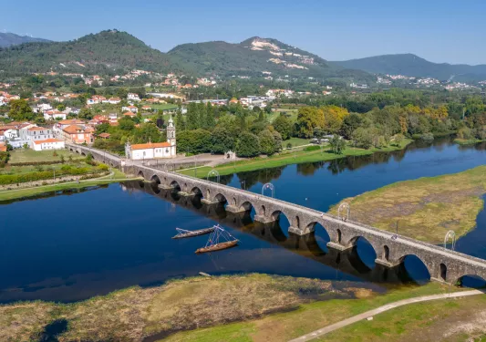 Long stone bridge with a river underneath, leading to a small town