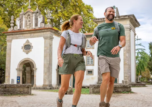 Man and woman smiling while walking on a stone path with a church building in the background