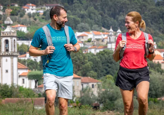Man and woman smiling at each other, while walking on a trail