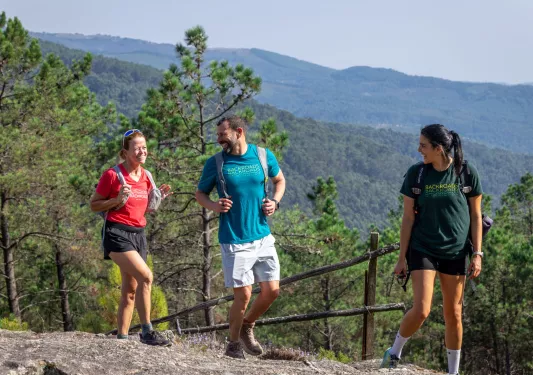 Man and two women smiling while hiking on top of a hill