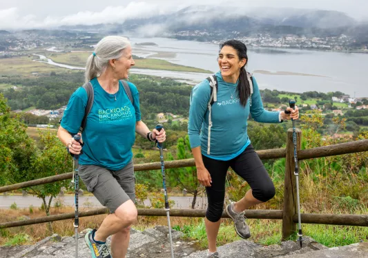 Two women smiling while walking up stairs on a hill