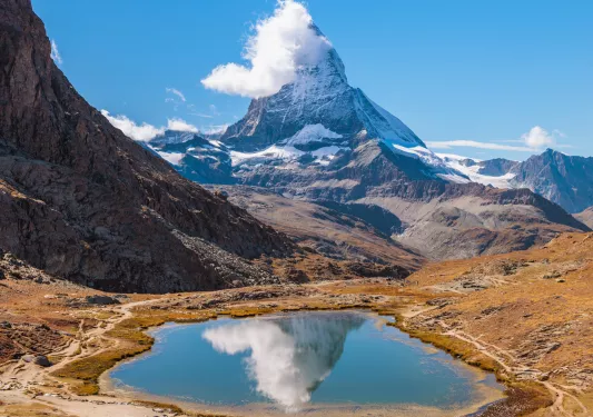 snow covered mountain with lake in front