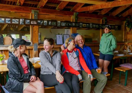 Group of people sitting on a bench indoors, laughing and smiling