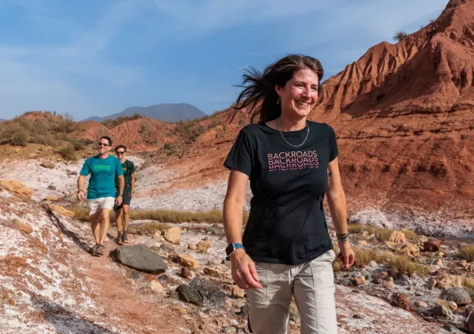 Woman and two men walking on a dirt trail, smiling