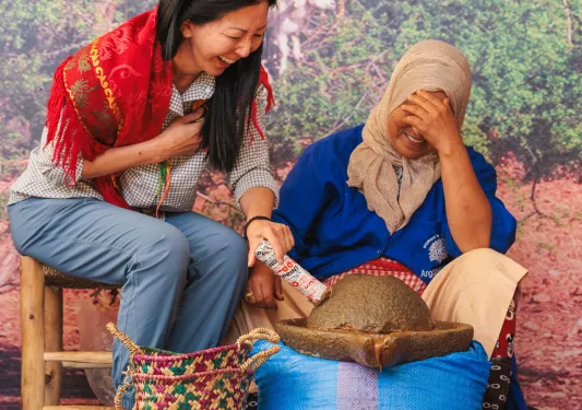 Two women smiling while sitting on wooden chairs