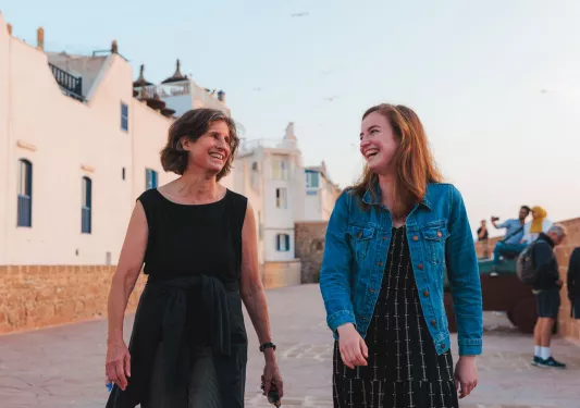 Two women smiling while walking in front of a large, white building