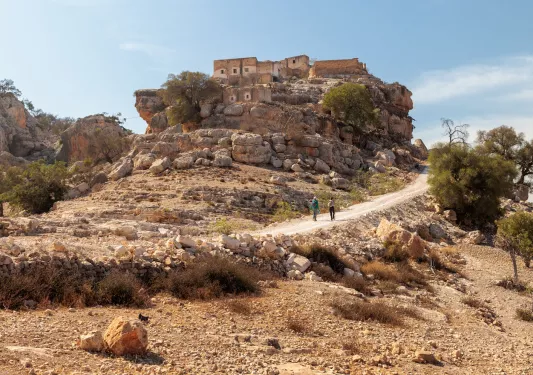 People in the distance walking up a trail on a cliff