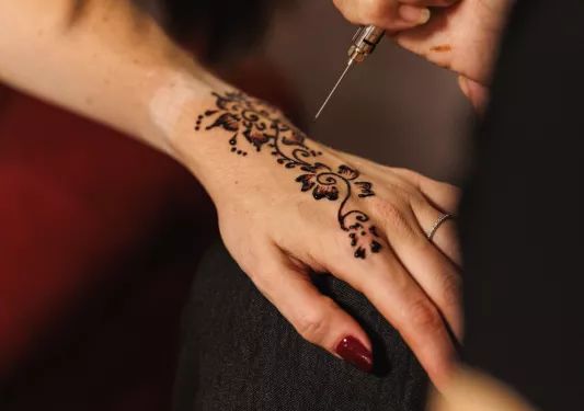 Person getting henna tattoos on their hand