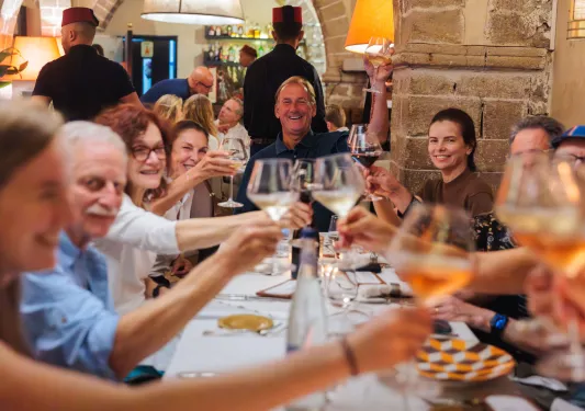 Group of people smiling while raising their glasses around a dining table