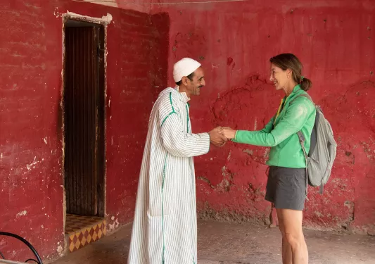 Woman and man holding hands in from of a red wall