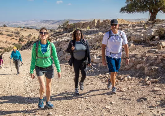 Group of people smiling while hiking up a gravel trail
