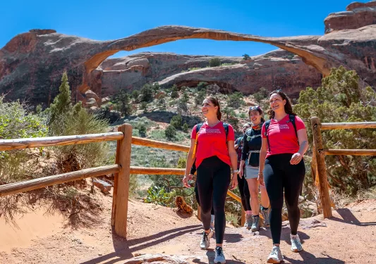 Group of women walking through a dirt trail surrounded by mountains and large canyons