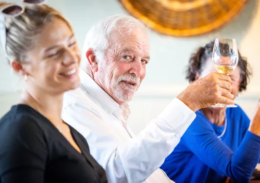 Older man holding up a glass of wine and smiling