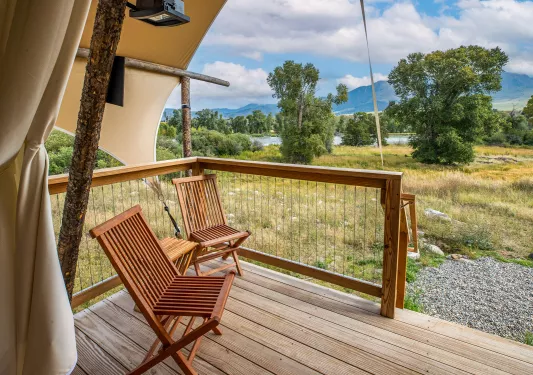 Outdoor, wooden patio with two wooden chairs looking out to a valley