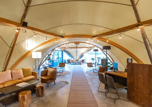 Inside of large, luxury tent with cushioned sofas and tables