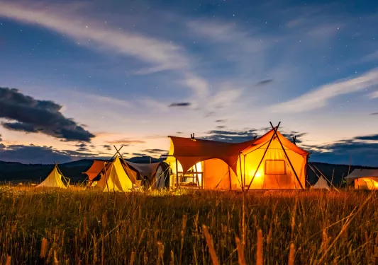 Exterior view of multiple luxury tents with orange, illuminated lights inside