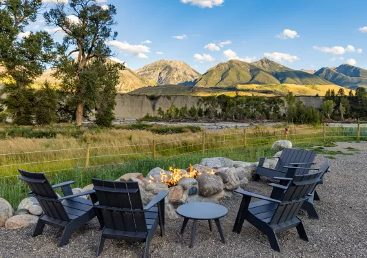 4 black chairs surrounding a firepit in the middle of a valley