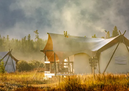 Luxury, white tent surrounded by fog and a forest in the background