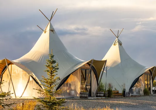 Two large luxury tents with cloudy skies above