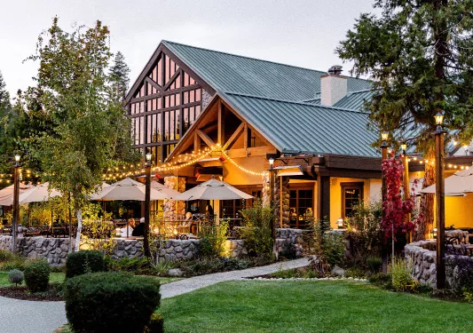 Exterior view of wooden cabin building with large windows, and an outdoor patio
