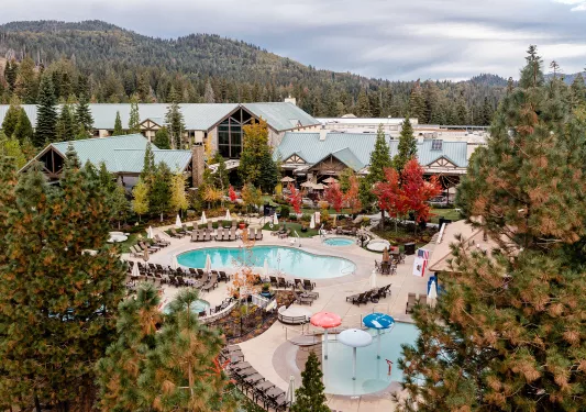 Exterior sky view of large wooden buildings with blue roofs, and outdoor pools in front
