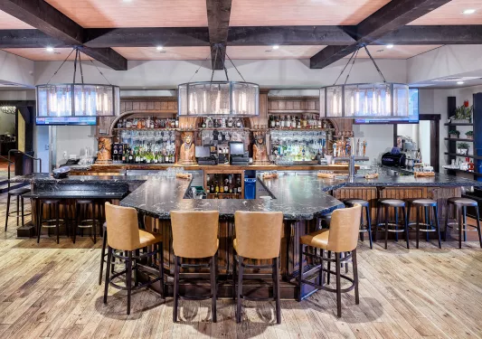 Indoor bar and lounge with a horseshoe-shaped marble counter and alcohol along the walls