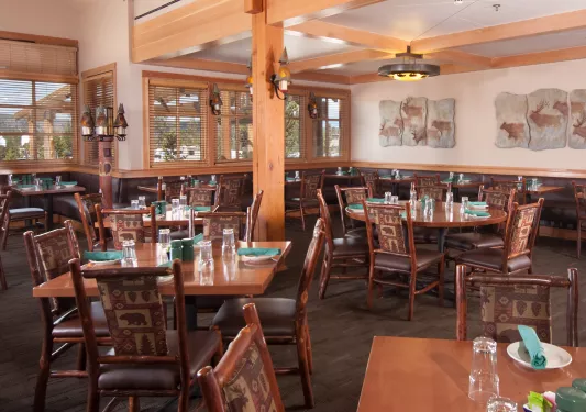 Lodge restaurant with wooden tables and chairs, and paintings on the walls