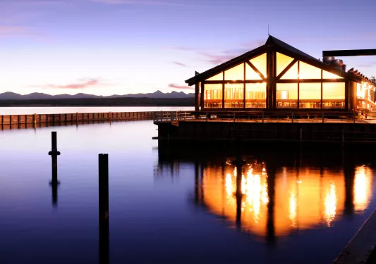 Sunset view of an illuminated building with a lake in front