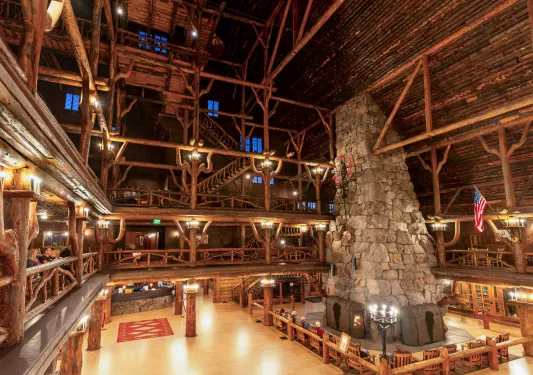 Large cabin with multiple floors and a large stone chimney and fireplace in the center